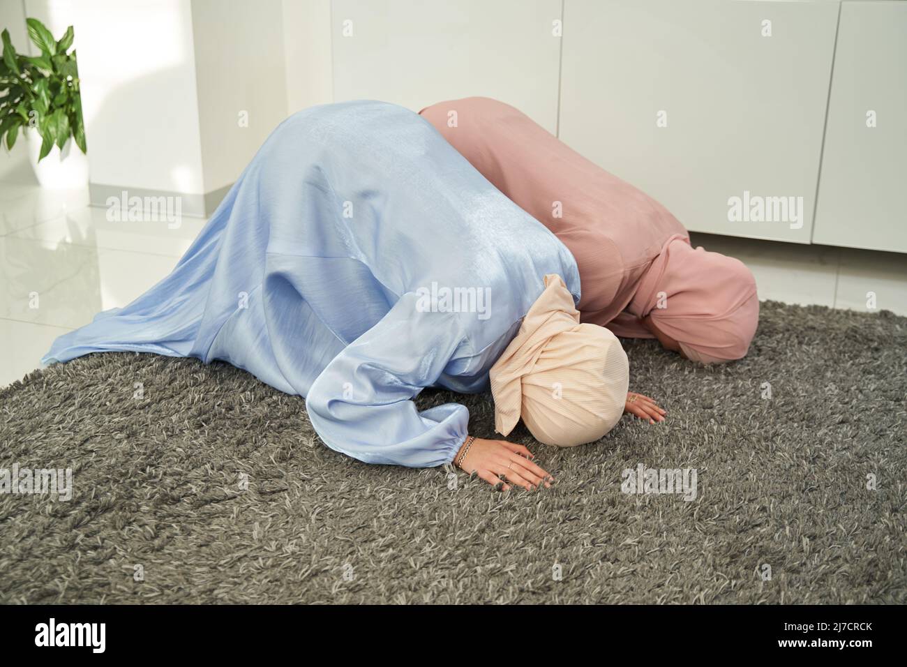 Muslim women performing sujud praying position at home Stock Photo