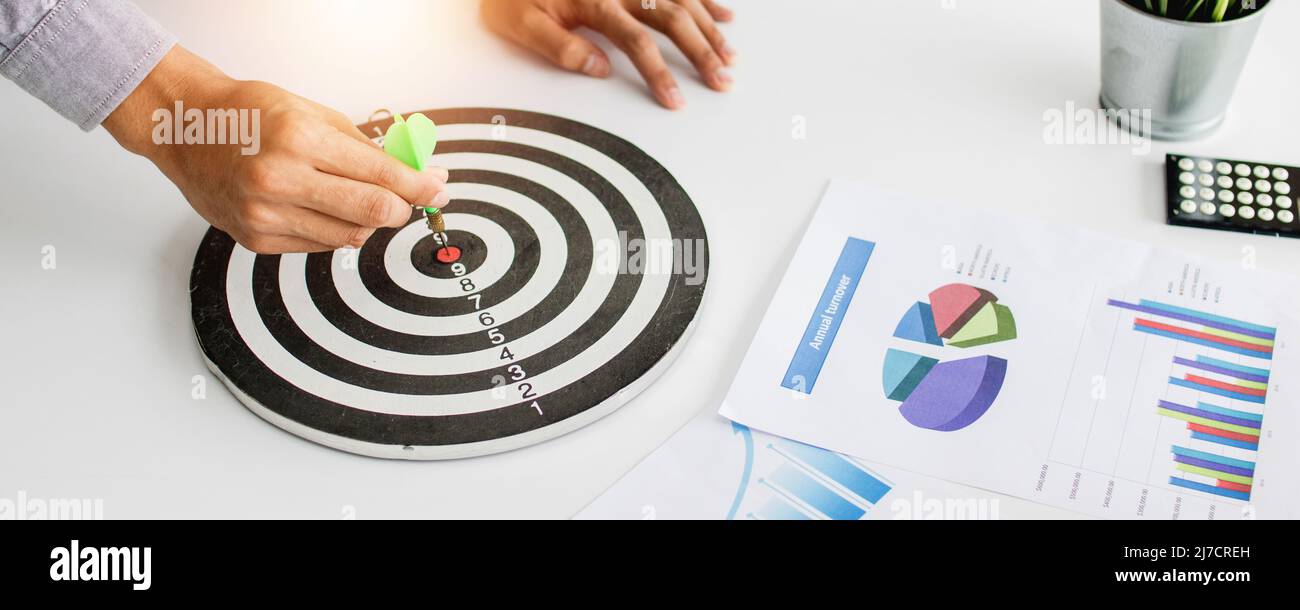 close up hand holding dart on target on table in office, success and goal concept Stock Photo