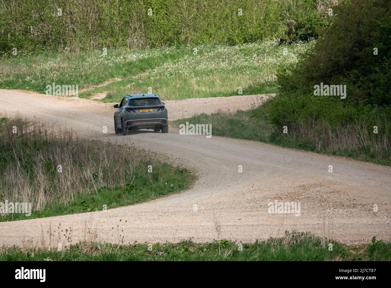 grey Hyundai Tucson sport utlility vehicle driving an unmade stone track in green countryside Stock Photo