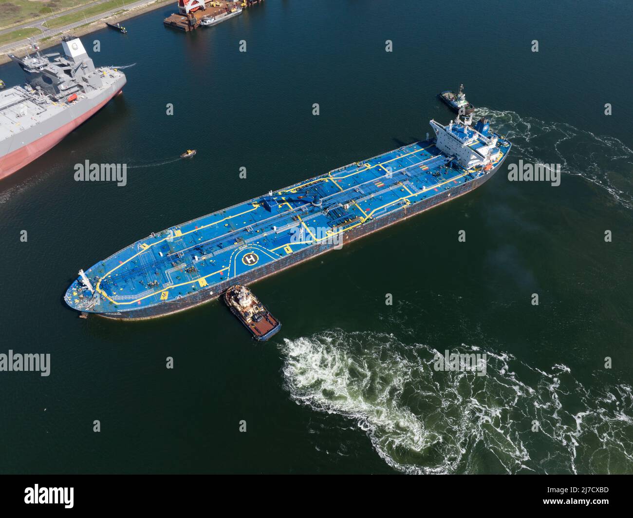 Rotterdam, 18th of april 2022, The Netherlands. Crude Oil Tanker ship Alhani being docked in the harbour by a tugboat marine vessel. Aerial drone view Stock Photo