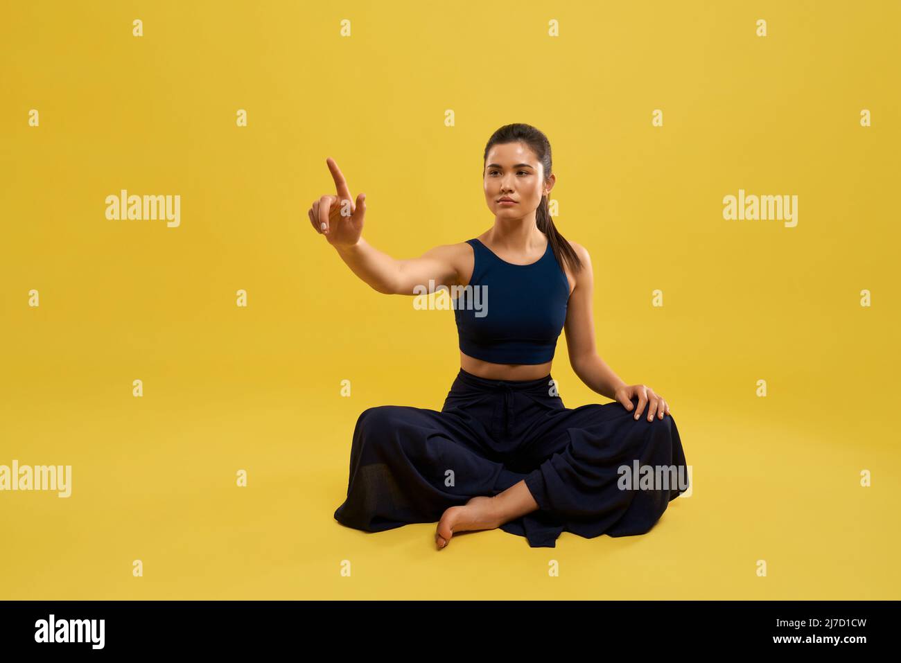 Front View Of Sporty Girl Sitting With Crossed Legs On Floor Raising 