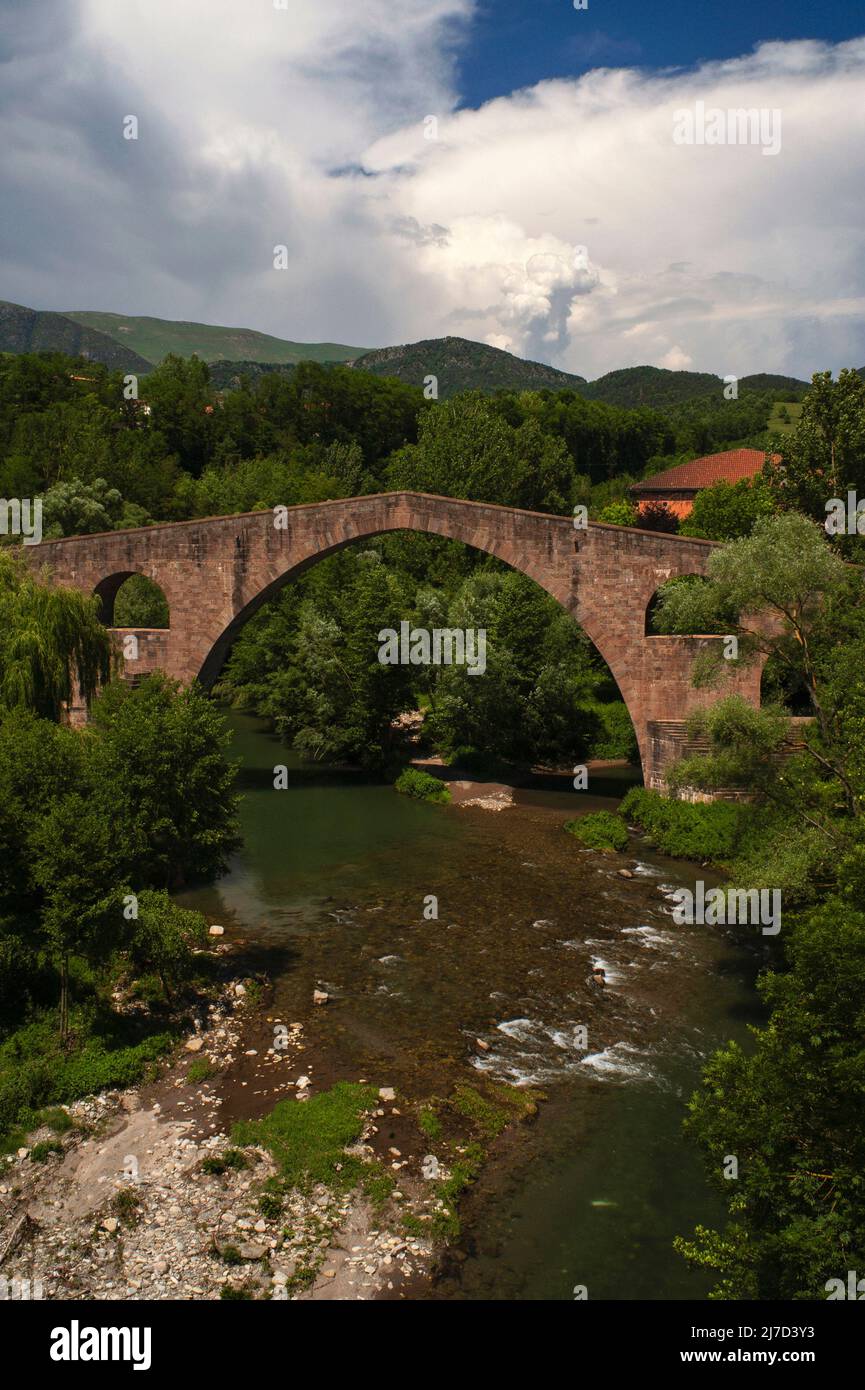 Dramatic stormy sky over the graceful arch of the Pont Vell or Old Bridge over the River Ter at Sant Joan de les Abadesses, Ripollès, Catalonia, Spain.  The 12th century bridge has been rebuilt several times, thanks to a 1428 earthquake and destruction wrought by retreating Republican troops during the Spanish Civil War. Stock Photo