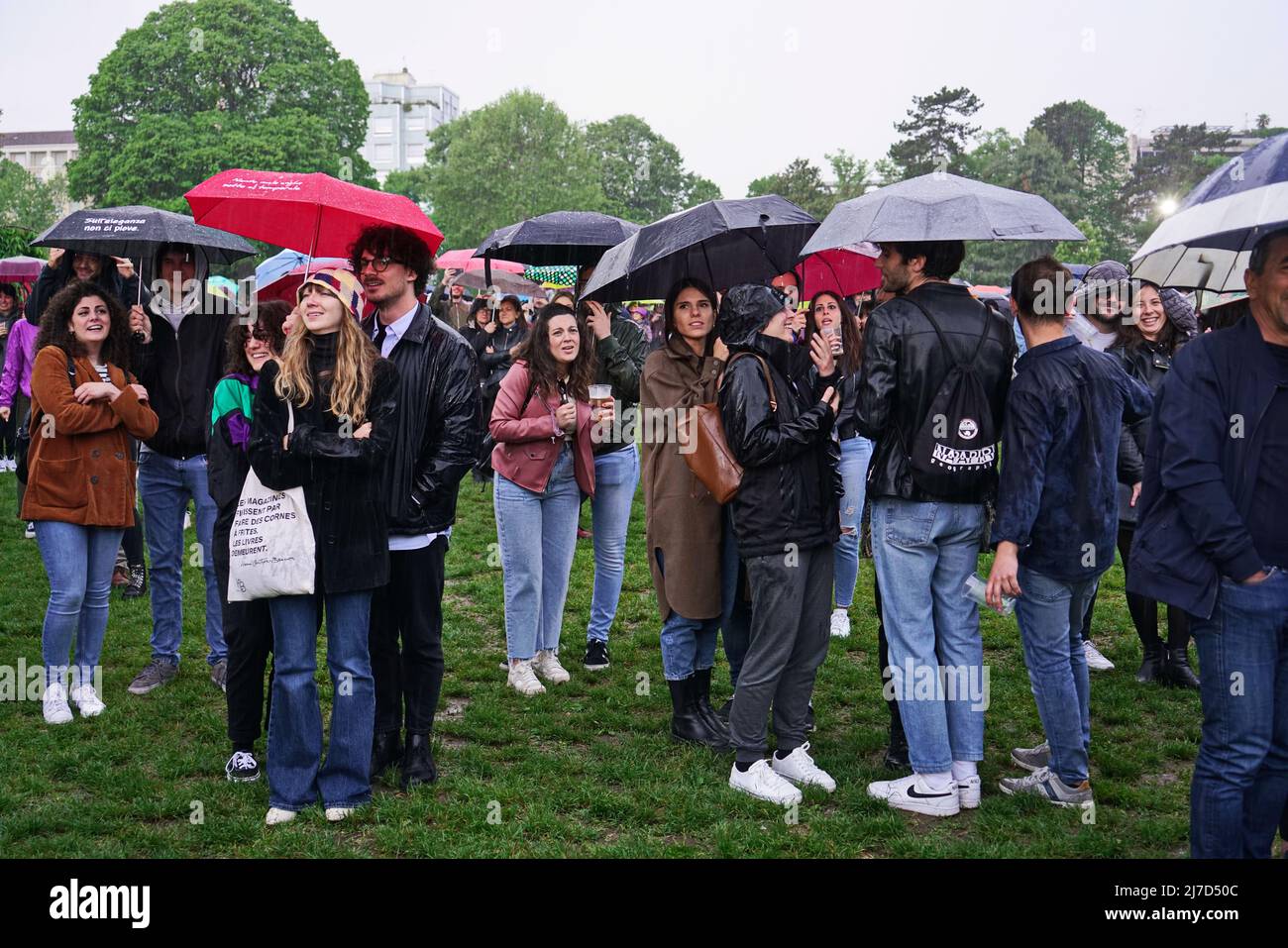 People at an outdoor event take cover from the rain with umbrellas. Turin, Italy - May 2022 Stock Photo