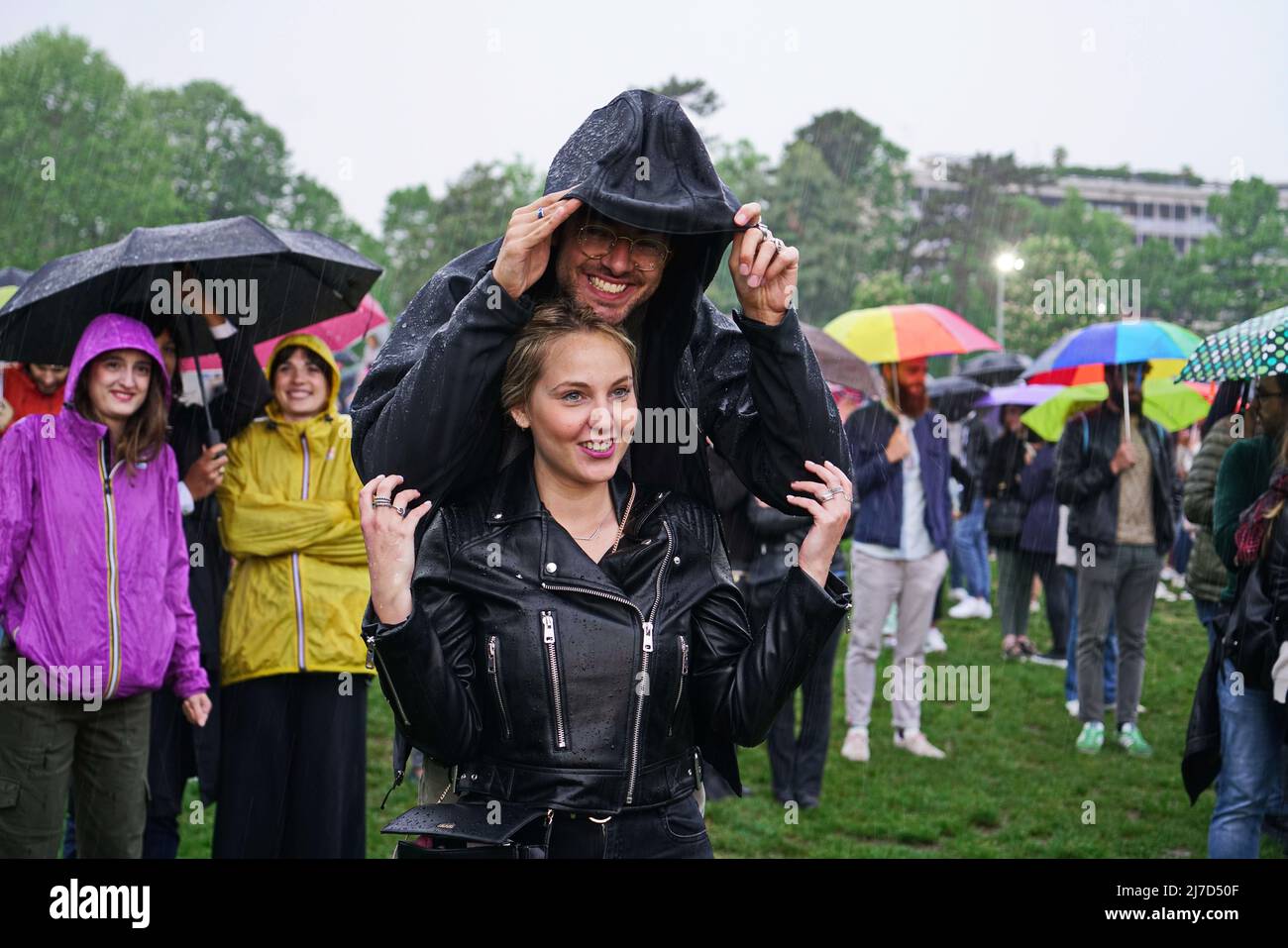 People at an outdoor event take cover from the rain with umbrellas. Turin, Italy - May 2022 Stock Photo