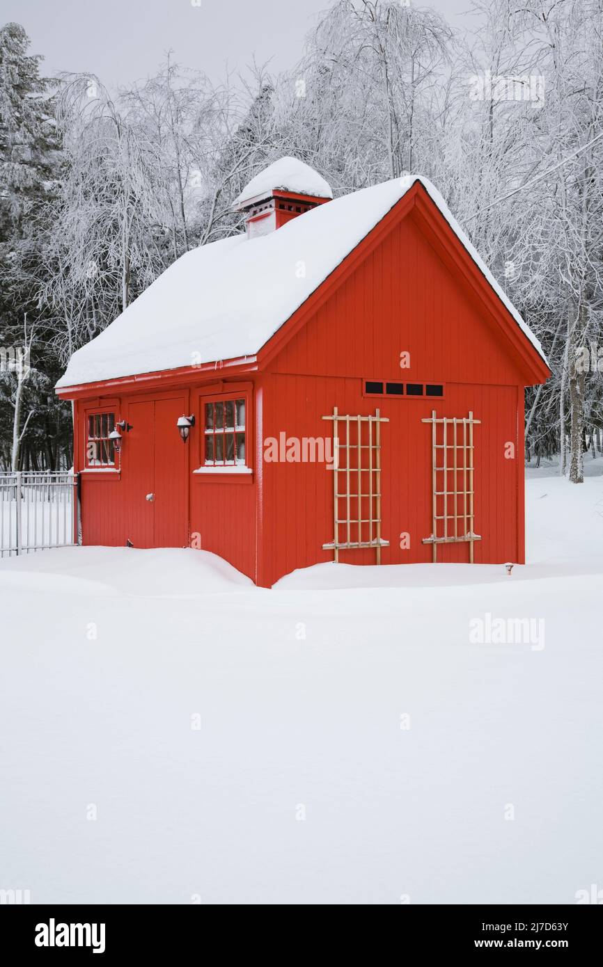 Red barn style storage shed with frost and snow covered trees in winter, Eastern Townships