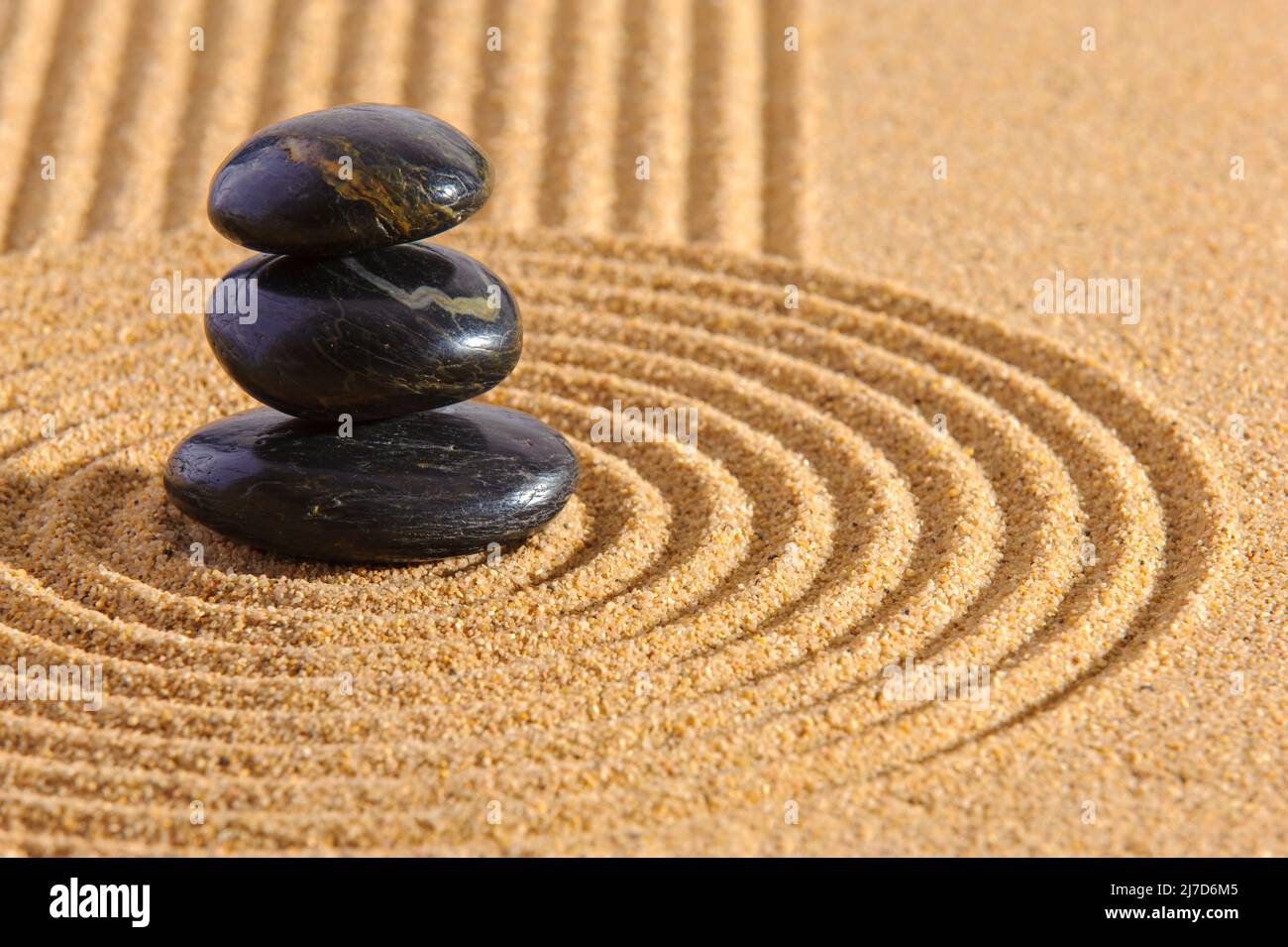 Japanese zen garden with yin yang stone in textured sand Stock Photo