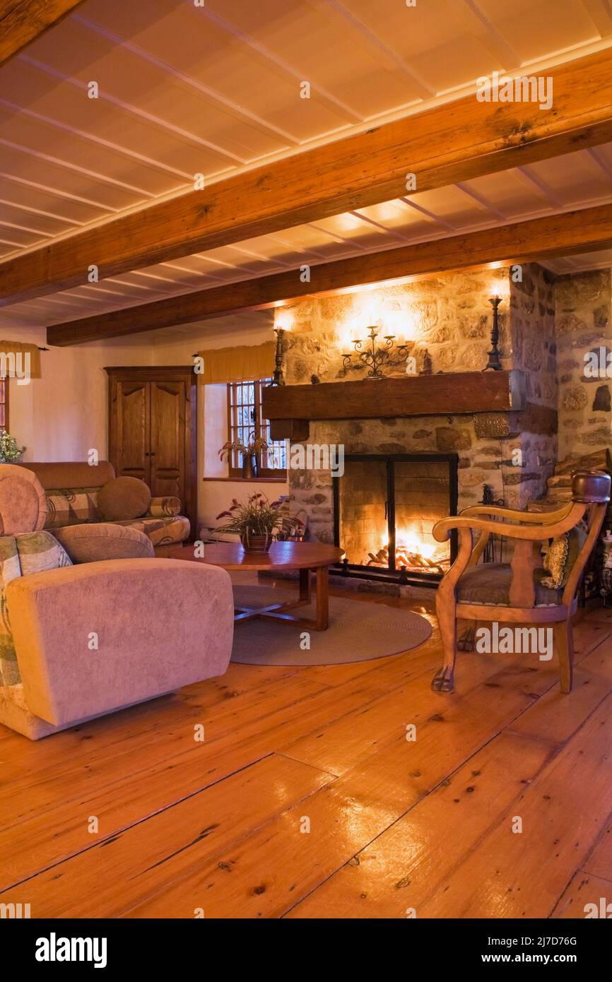 Lit stone fireplace and antique furnishings in living room inside 1800s log home Stock Photo Alamy