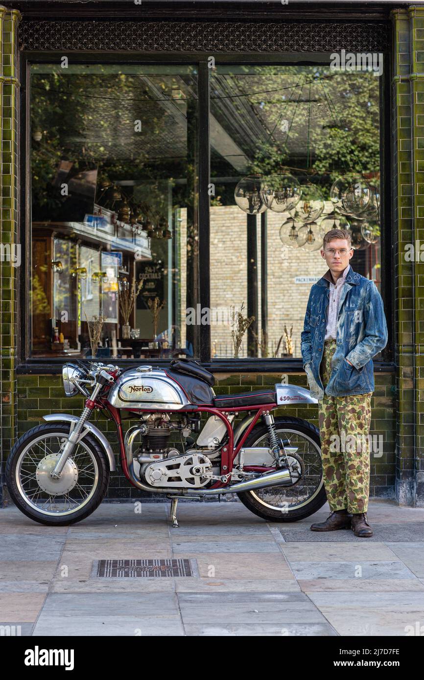 Stylish man wearing camouflage pants out side pub with classic motorcycle Stock Photo
