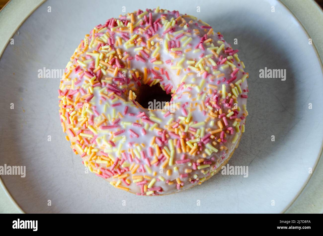 A ring donut glazed with sprinkles Stock Photo Alamy