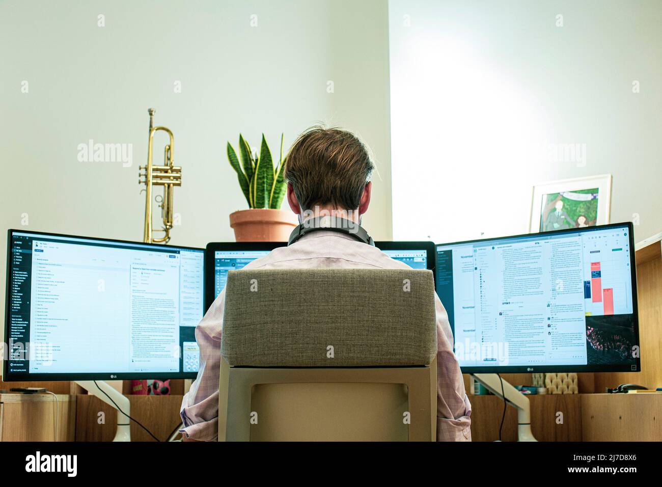 casual young man with headset using computer in a office. Back view. Stock Photo