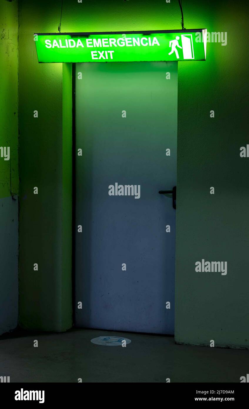 Door with illuminated emergency exit sign, in Spanish and English Stock