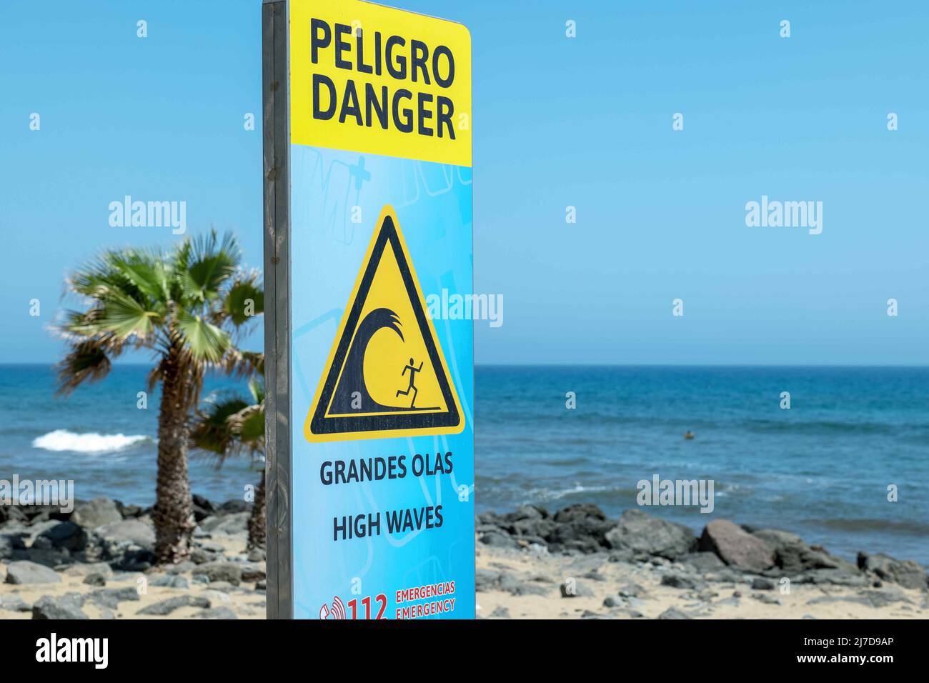 Warning sign on the beach about high waves, Spanish and English. Stock Photo