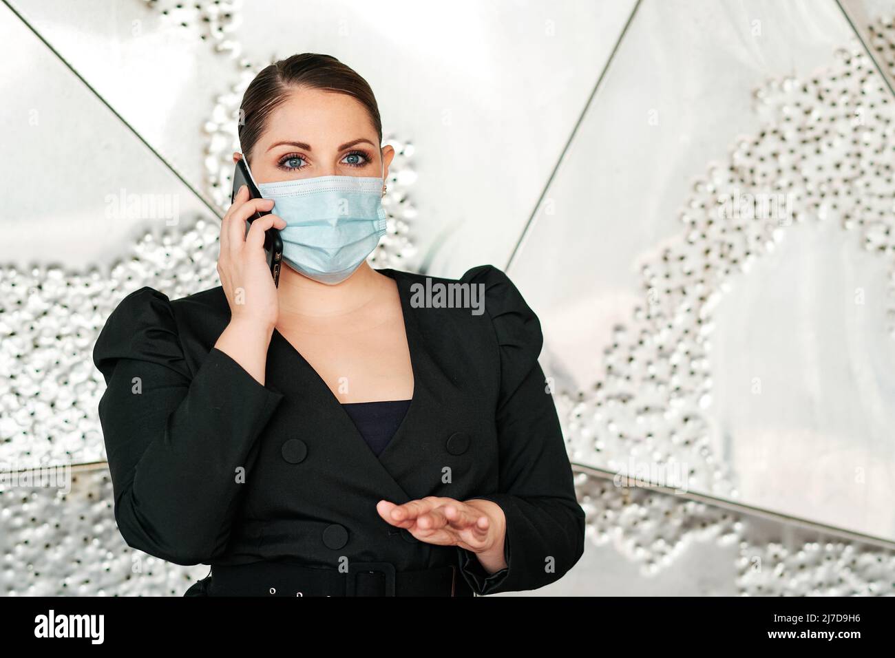 Executive woman using a face mask while talking on the mobile phone. Stock Photo
