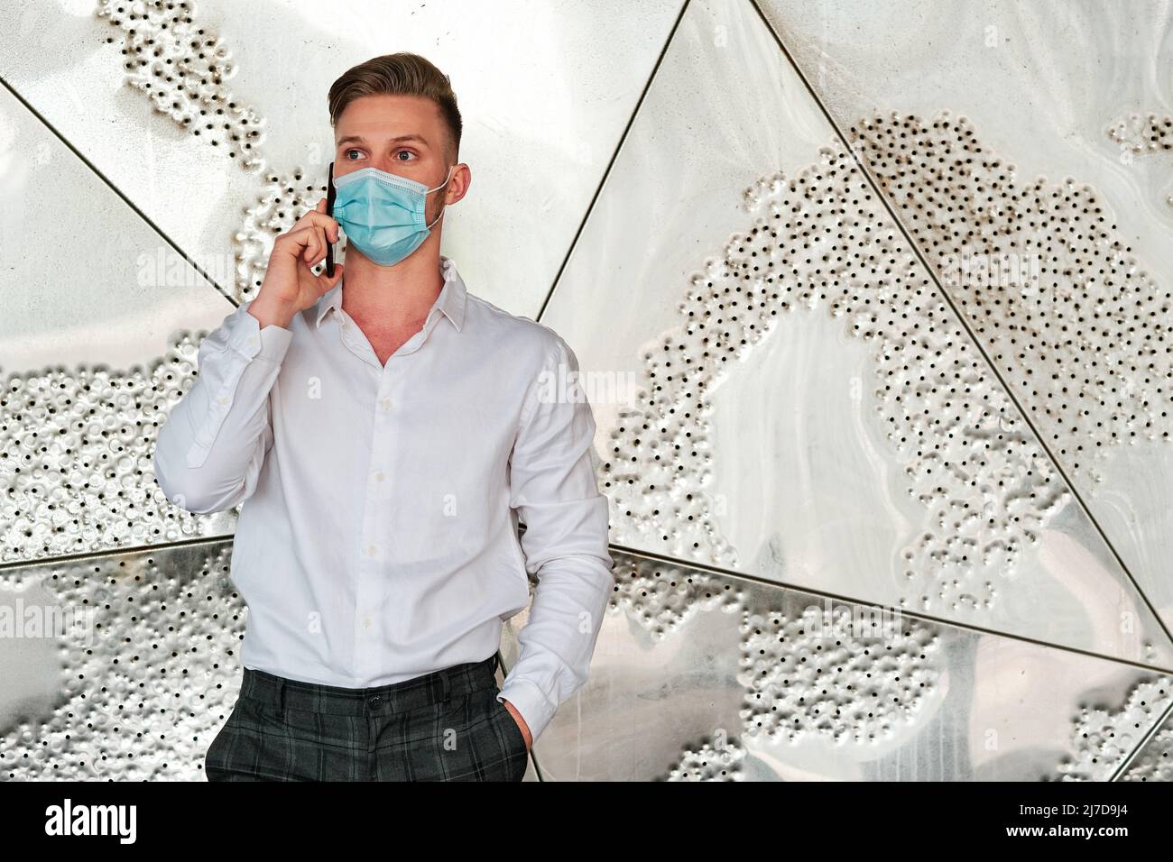 Executive man using a face mask while talking on the mobile phone. Stock Photo