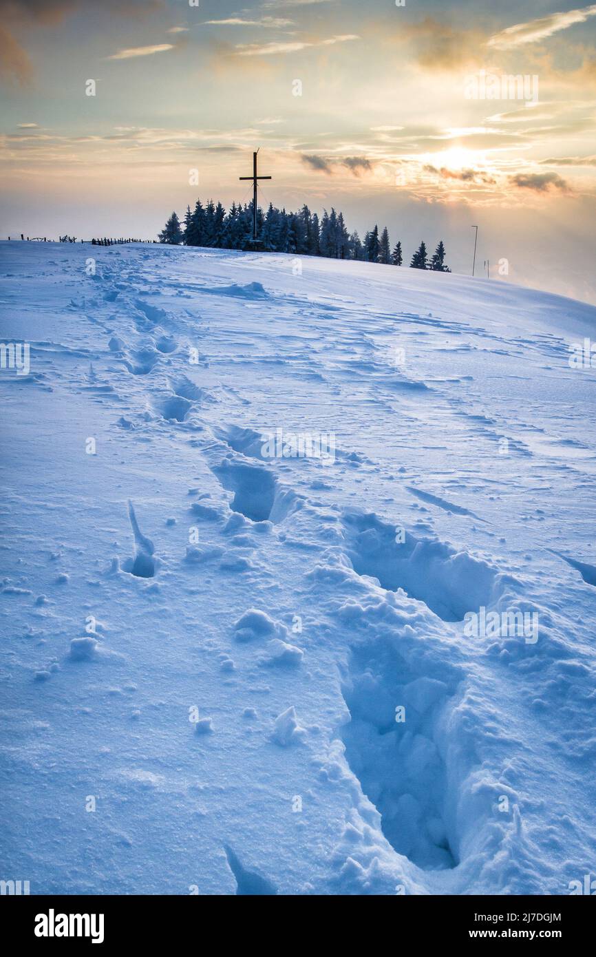 Foot steps in the snow leading to the summit cross at the Schoeckl mountain in Austria near Graz Stock Photo