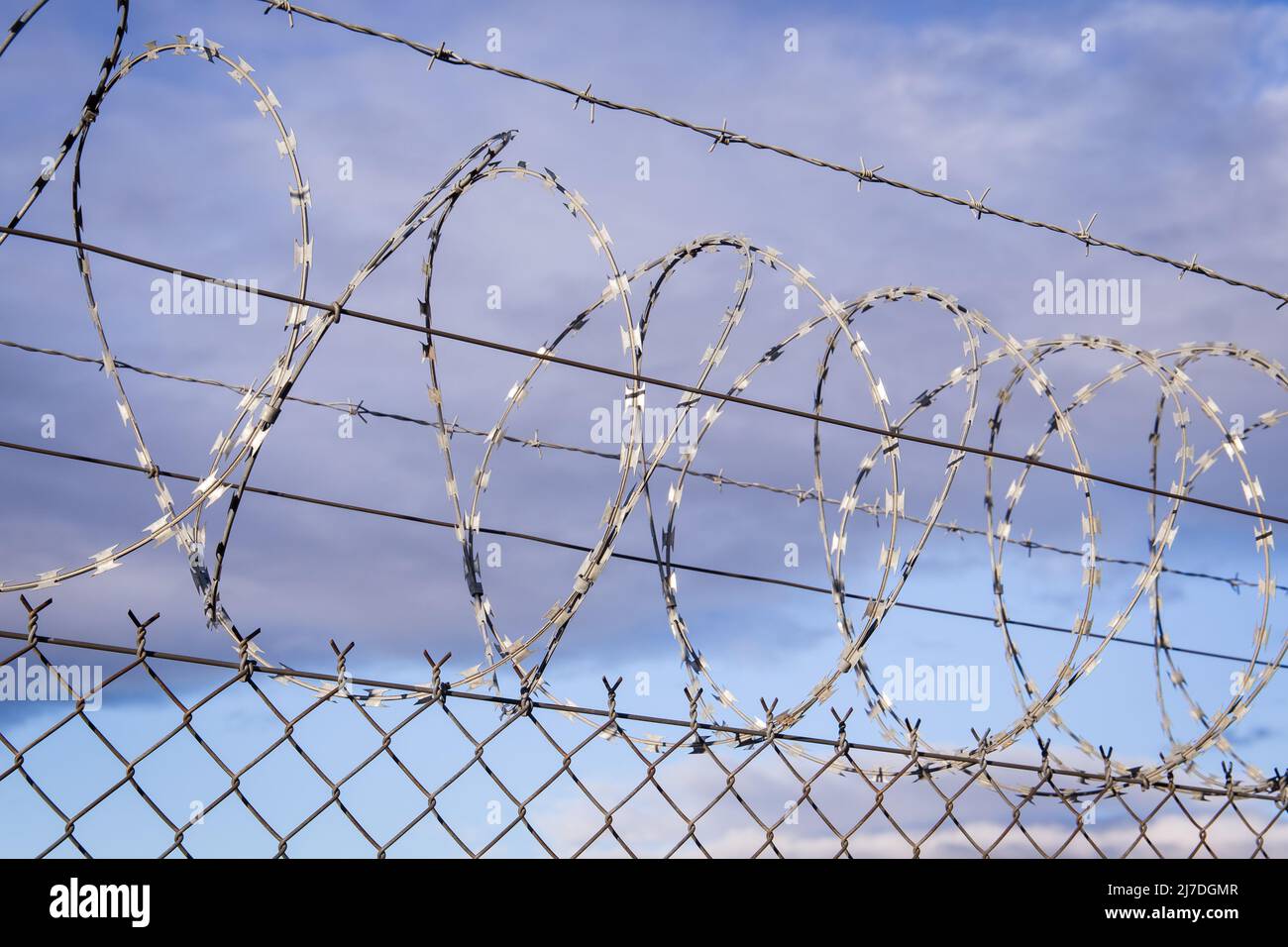 Closeup focus view of NATO barb wire with sharp and dangerous razor blades Stock Photo