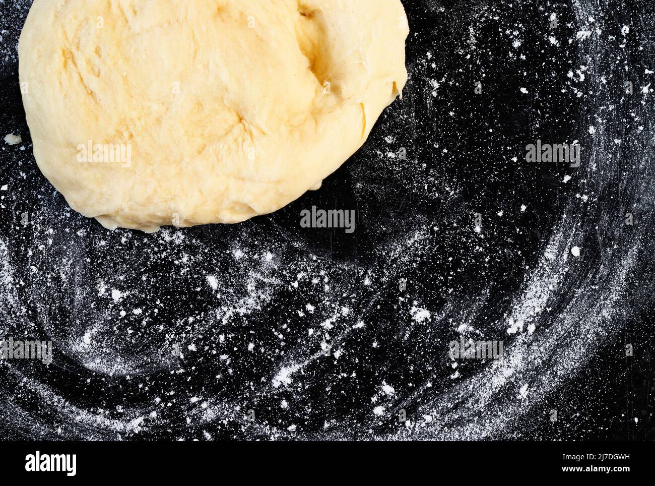 Raw dough on floured black surface ,baker occupation Stock Photo
