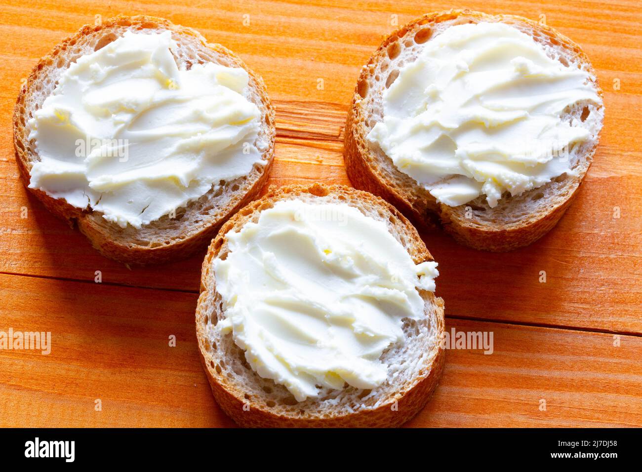 Sandwiches with cream cheese on the table. Sliced bread slices with soft cheese spread. Paste spread on a fresh French baguette. Homemade dessert Stock Photo