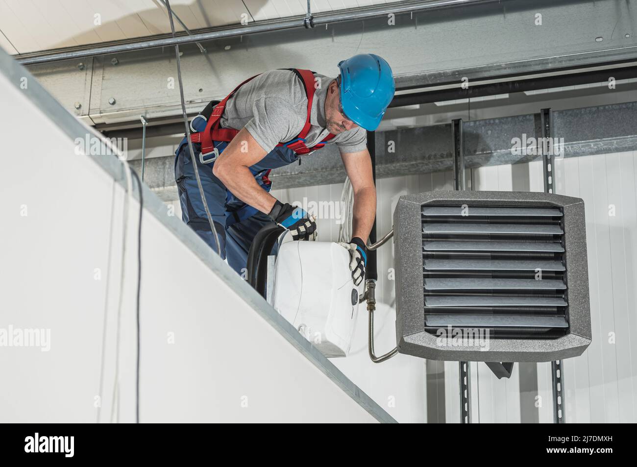 Caucasian HVAC Technician Worker in His 40s Installing Air and Water Heaters Inside Newly Constructed Warehouse. Stock Photo
