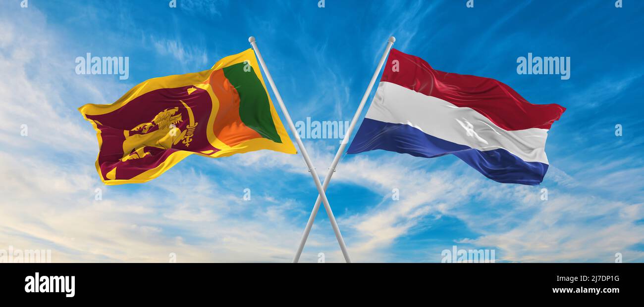 two crossed flags Sri Lanka and Netherland waving in wind at cloudy sky ...