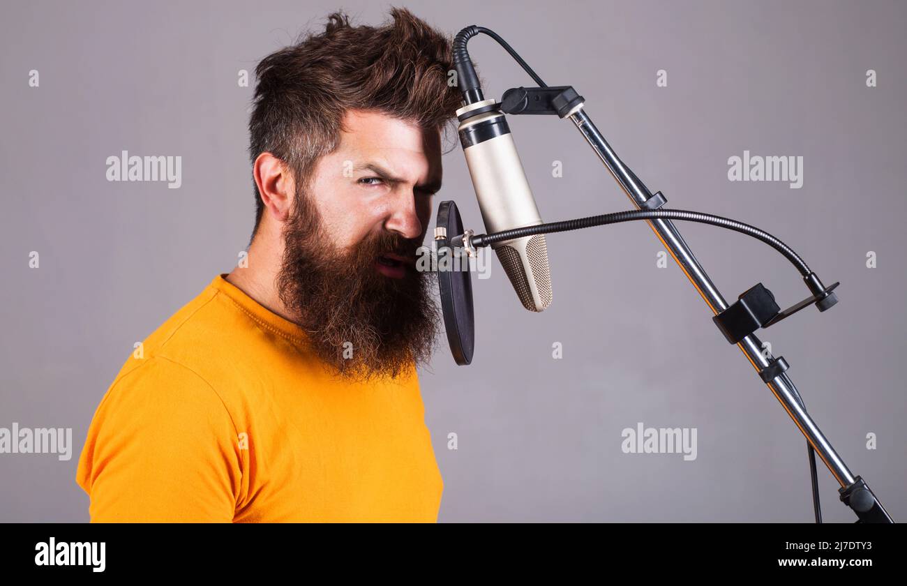 Male professional vocalist in Studio. Music production. Bearded man sing in condenser microphone. Stock Photo