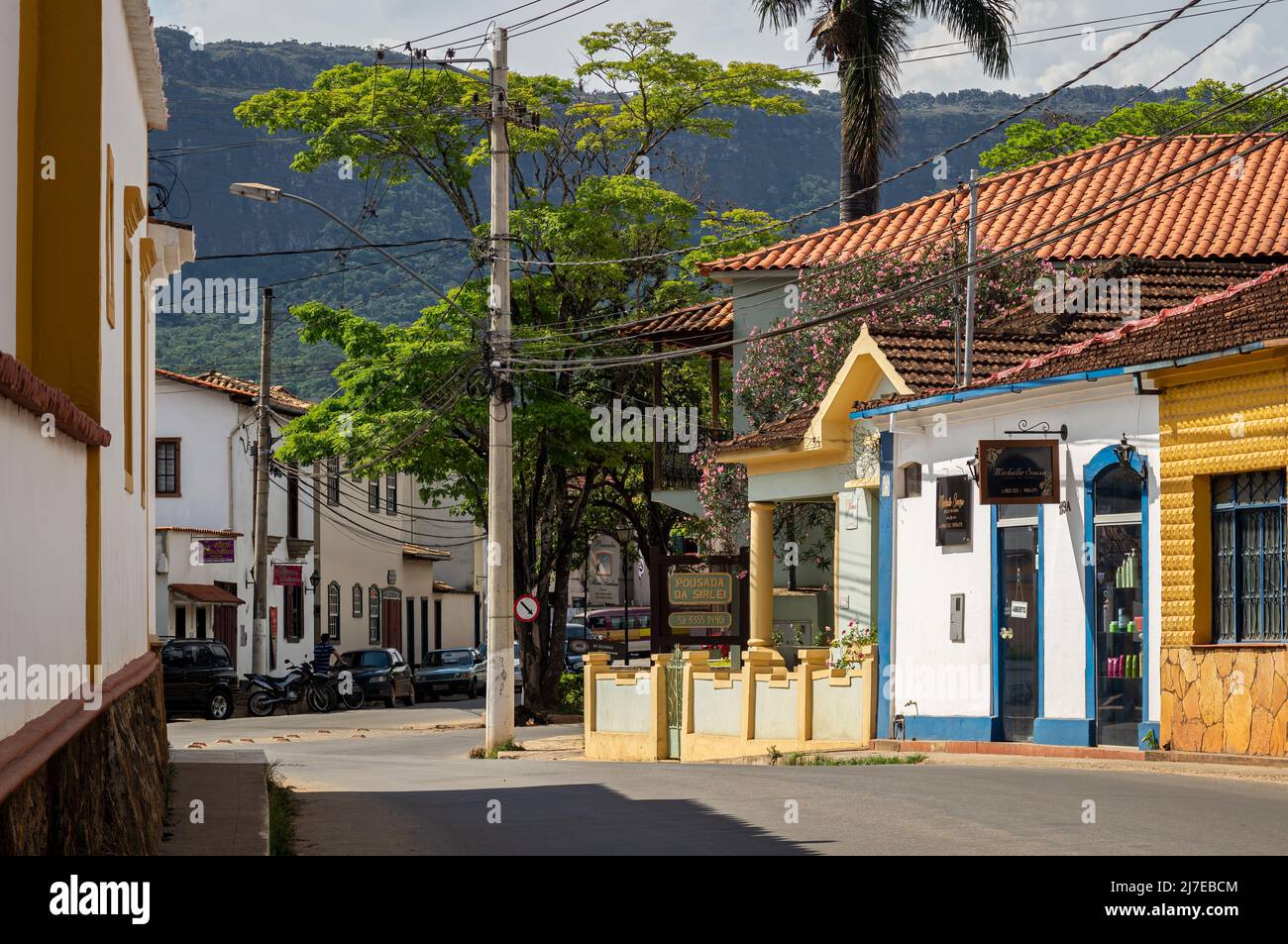 Various inns running in colorful colonial houses located at Antonio Teixeira Carvalho street, nearby historical center under clouded sunny sky. Stock Photo
