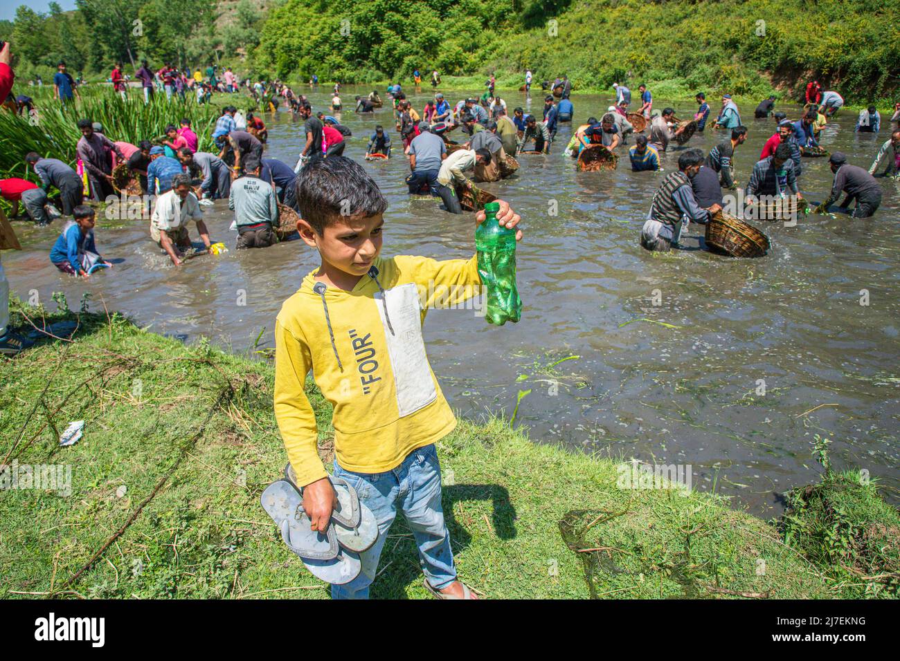 A boy shows off a bottle filled with fish as hundreds of Kashmiri