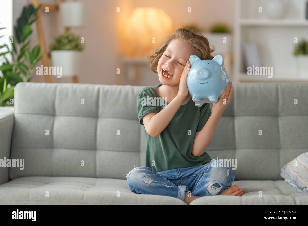 Happy girl with piggy bank. Child is smiling Stock Photo - Alamy