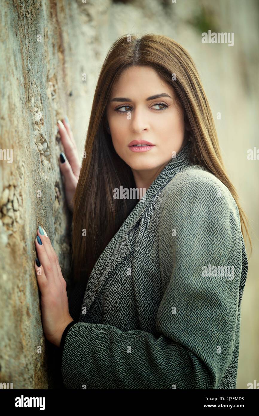 Worried woman leaning against the wall looking away outdoors Stock