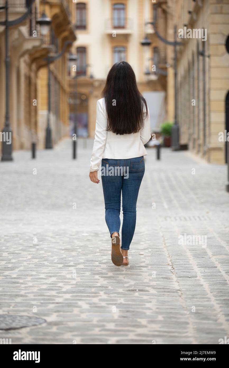 Rear view of woman walking away in the street Stock Photo - Alamy
