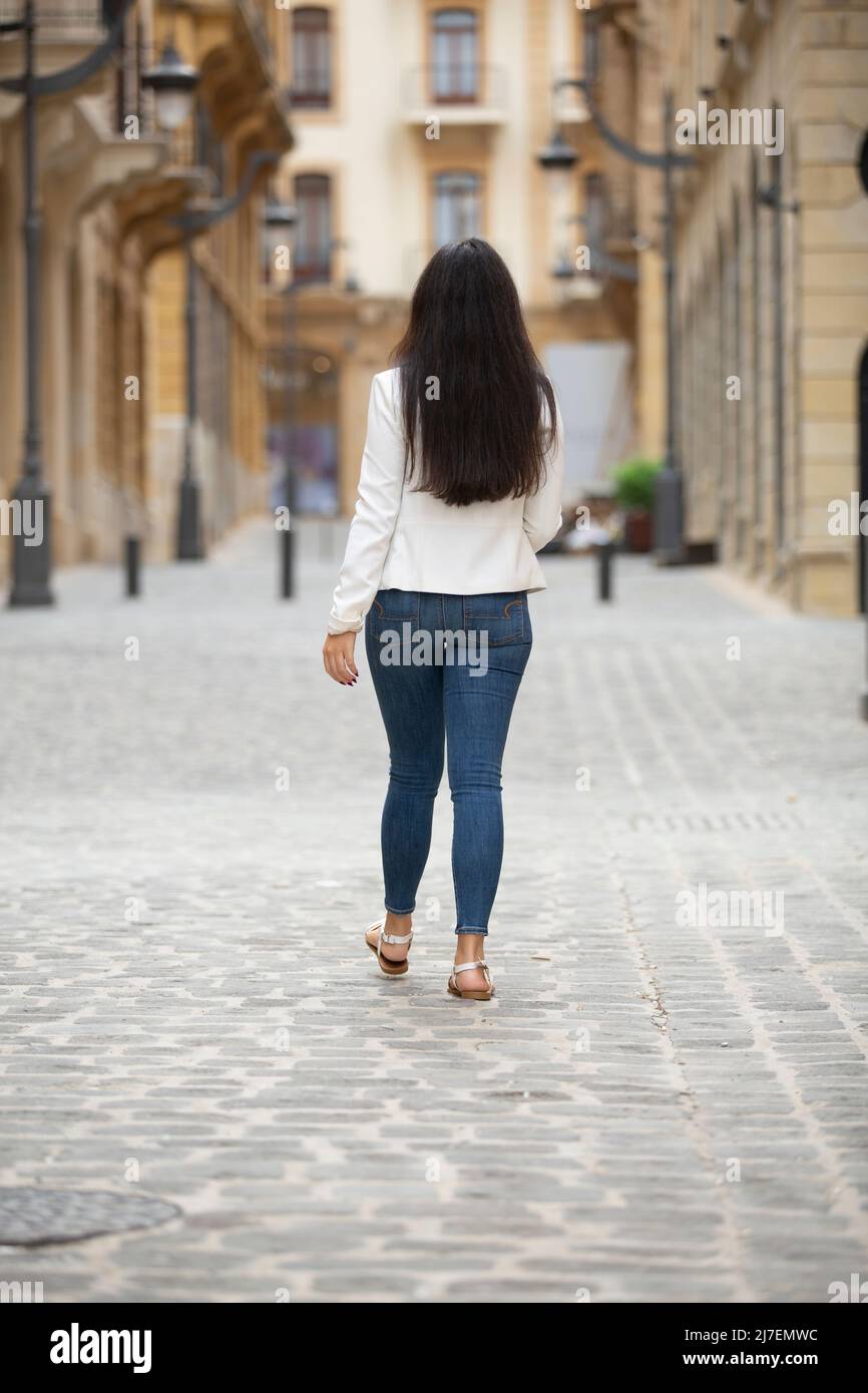 Rear view of woman walking away in the street Stock Photo