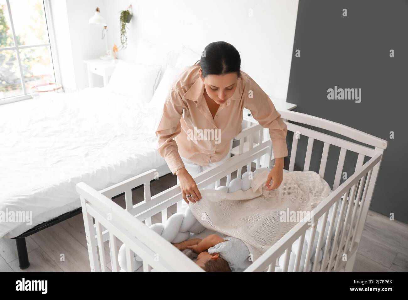 Young mother covering her sleeping baby with blanket in crib at home Stock Photo Alamy
