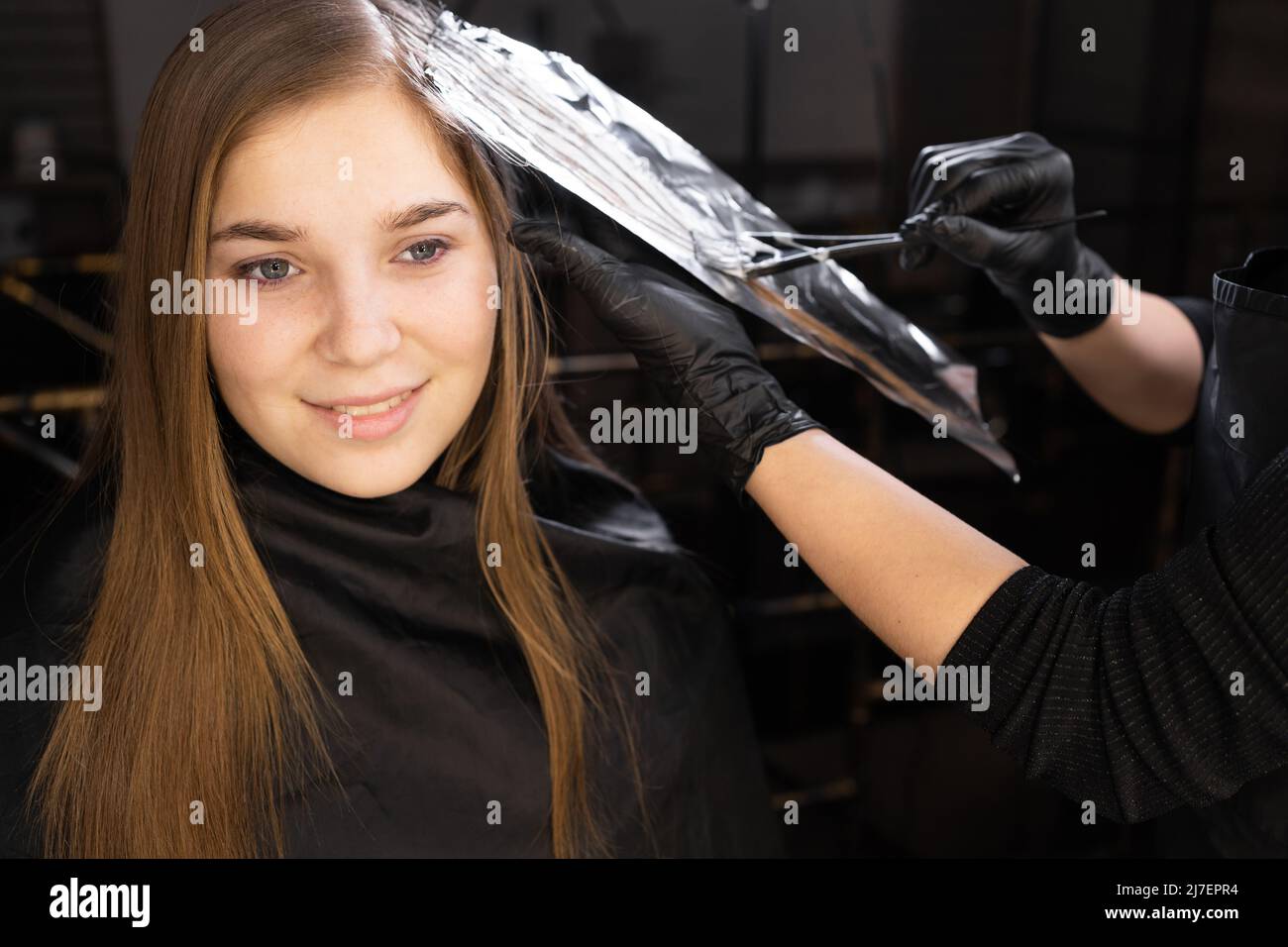 Foil on models hair. Bleaching or dyeing process. Beauty salon, fashionable  hair coloring. Copy space Stock Photo