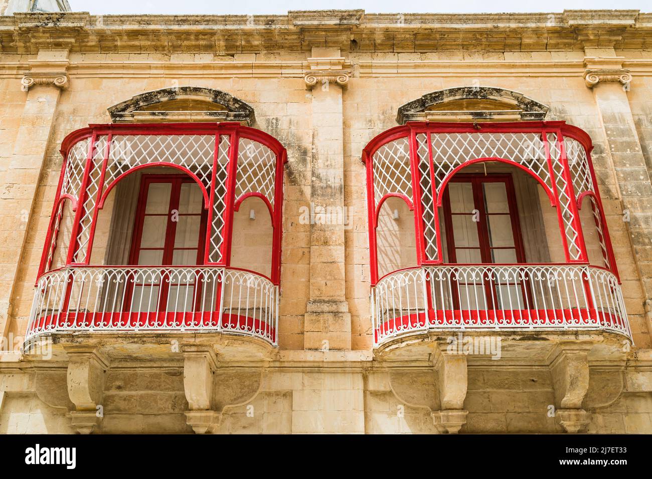 Looking up at a pair of pretty red balconies in mdina the old capital