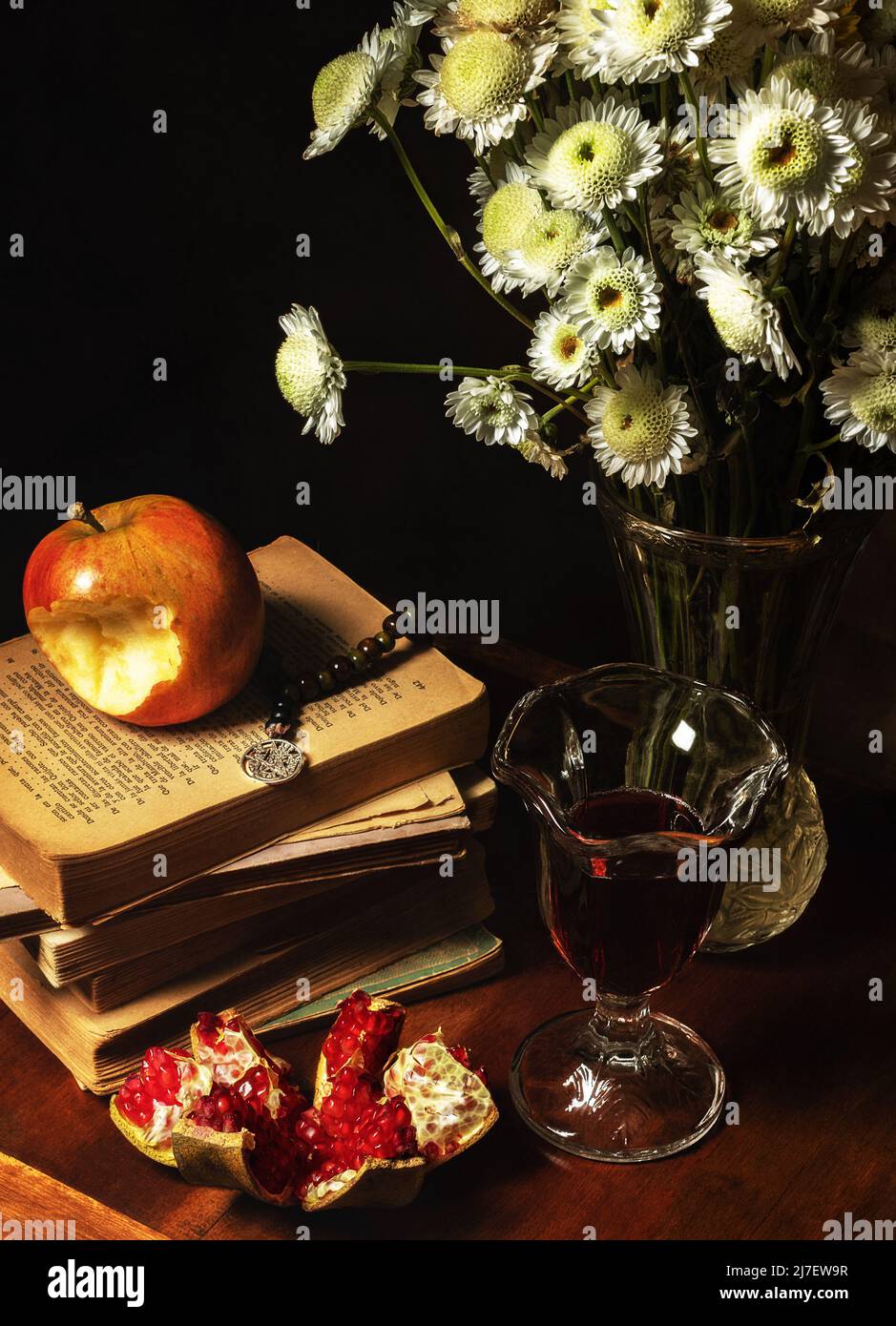 Bodegón de margaritas, manzana, granadas, libro y vino. / Still life of daisies, apple, pomegranates, book and wine. / Stock Photo