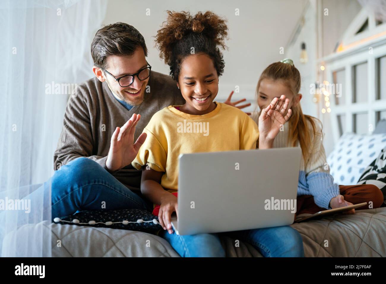 Multiethnic happy children and father studying at home for online school Stock Photo