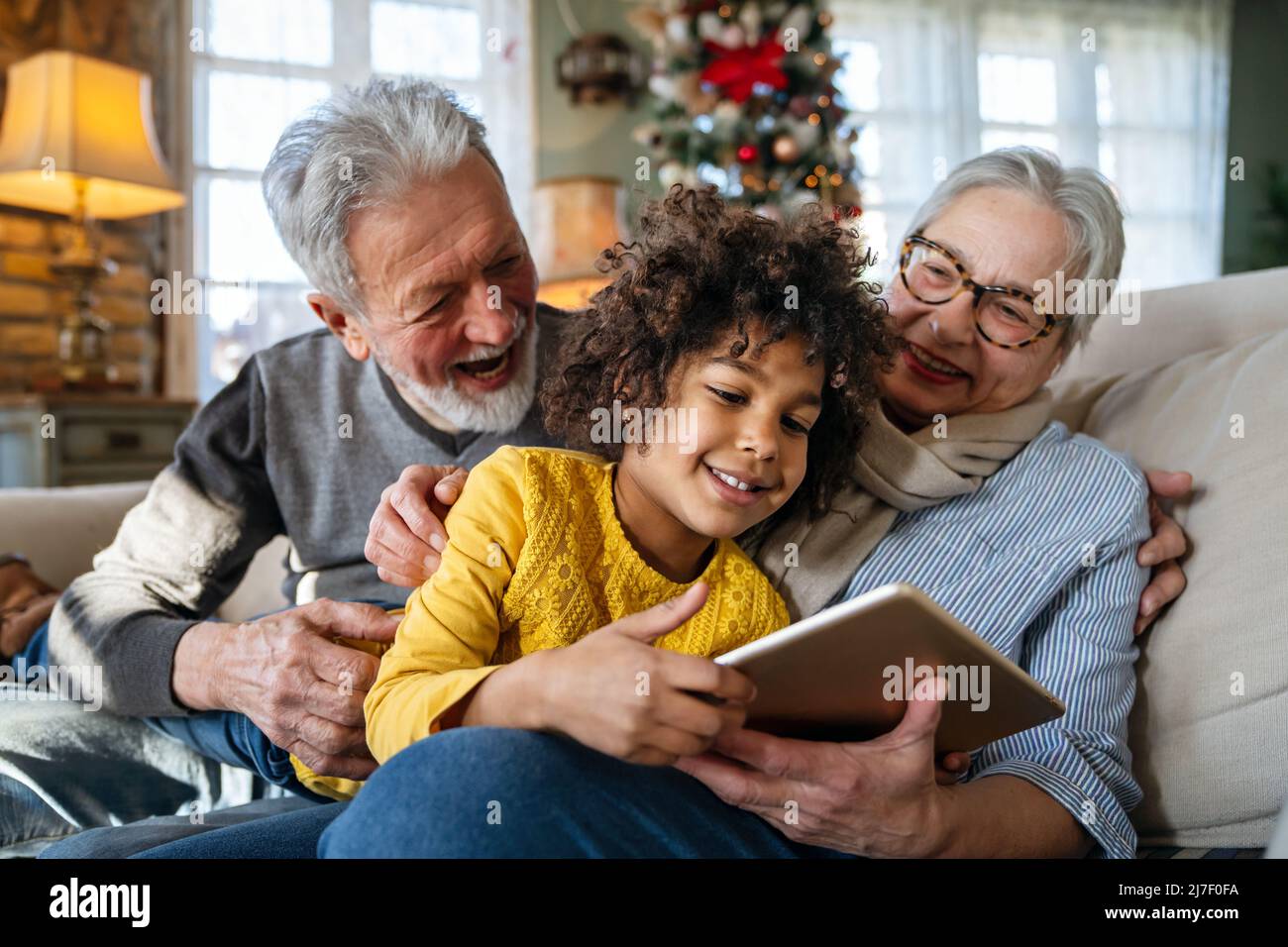 Portrait of happy grandparents with little girl using digital tablet at home Stock Photo