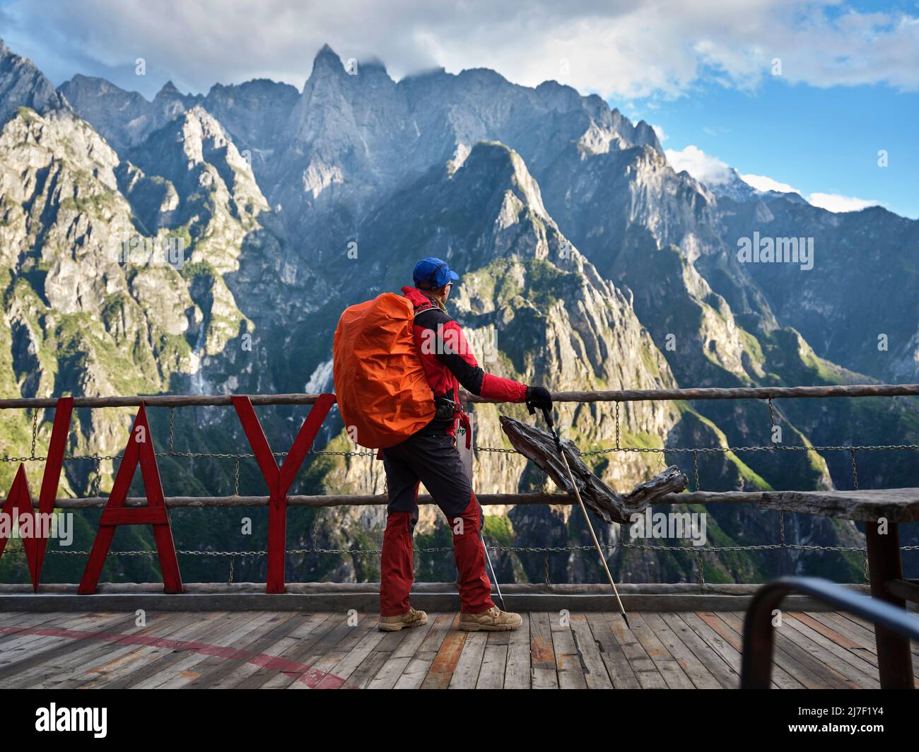 rear view of asian hiker trekker with walking stick standing on viewing platform looking at mountain Stock Photo