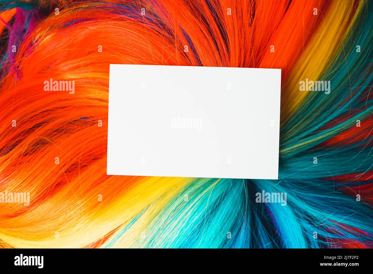 Mock up of a close business white card over a colorful, multi colored rainbow wig with a lot of hair texture Stock Photo