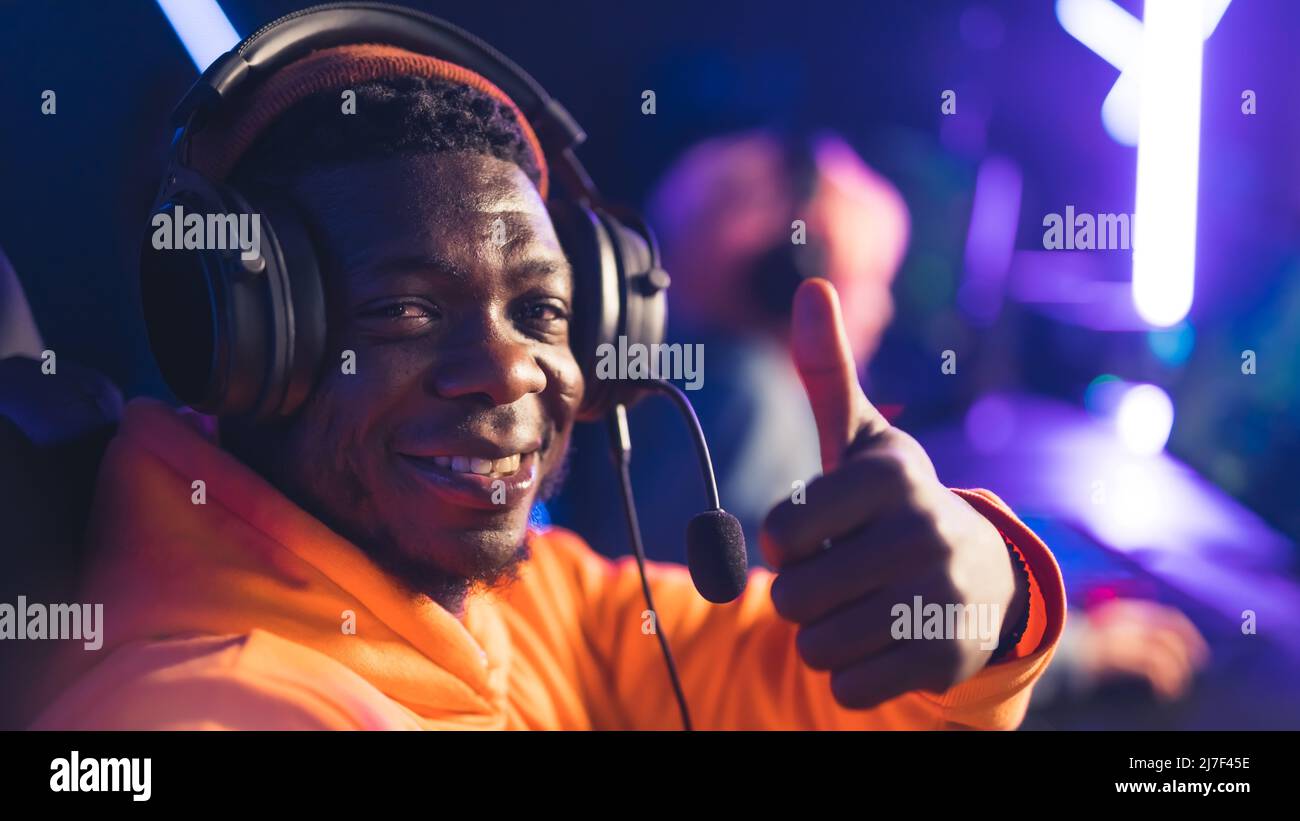 portrait of a happy Afro-American male gamer showing ok sign, thumb up closeup cybersport concept indoors . High quality photo Stock Photo