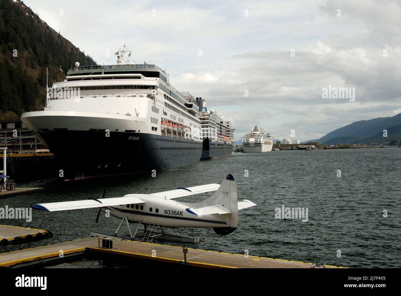 Seaplanes line up beside modern cruise ships at the Juneau waterfront. Stock Photo
