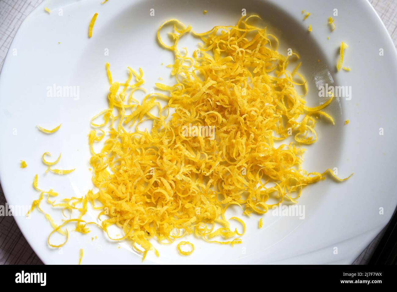 Lemon zest in a white plate, aromatic citrus peel goes well with many dishes and gives a fresh taste, copy space, high angel view from above, selected Stock Photo