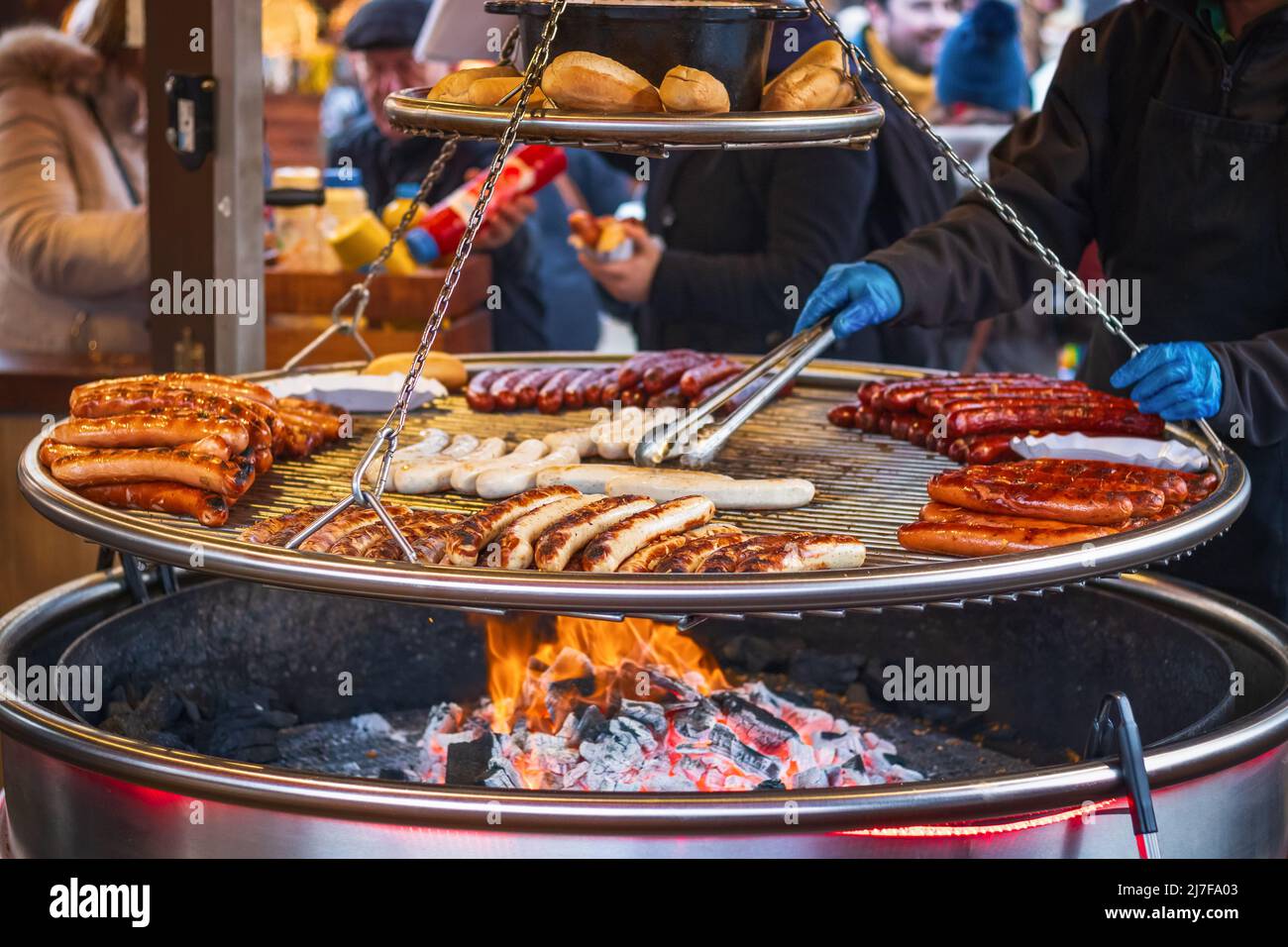 Grilling sausages on barbecue grill at a food stall of Christmas market in Hyde Park Winter Wonderland in London Stock Photo