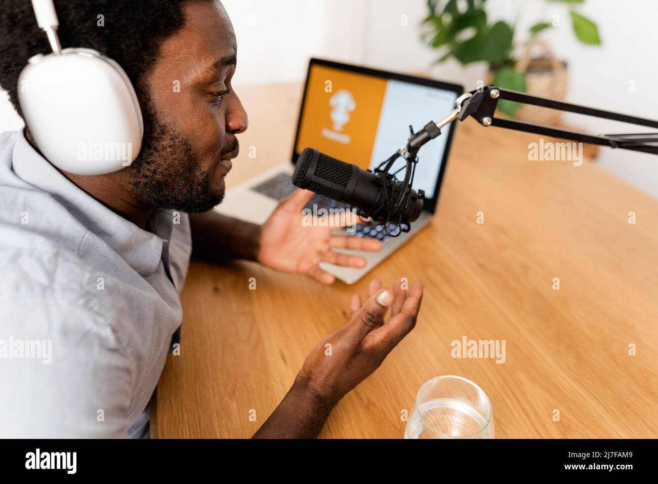 African man recording a podcast using microphone and laptop from his home studio Stock Photo