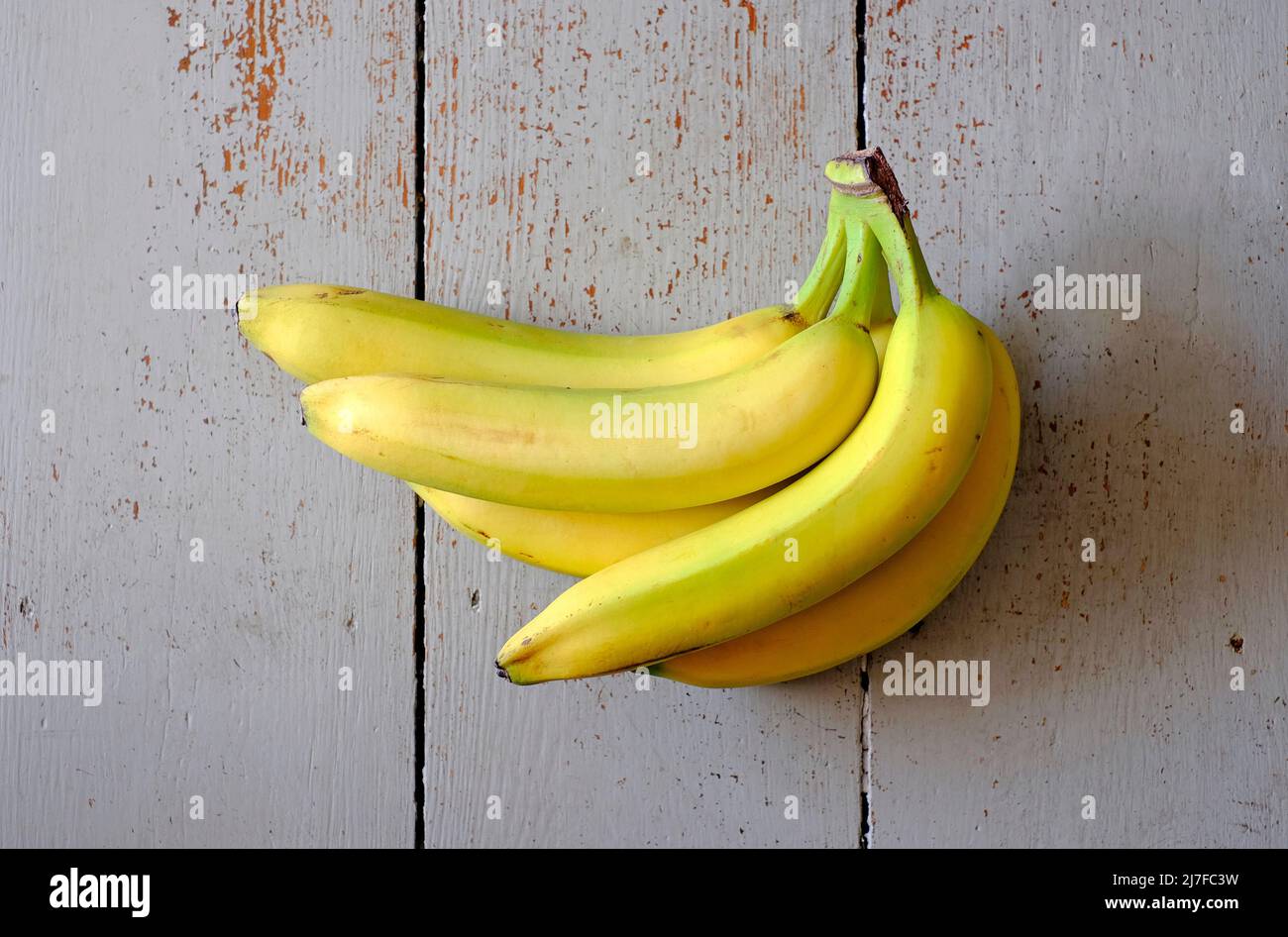 bunch of yellow bananas on grey painted table top Stock Photo
