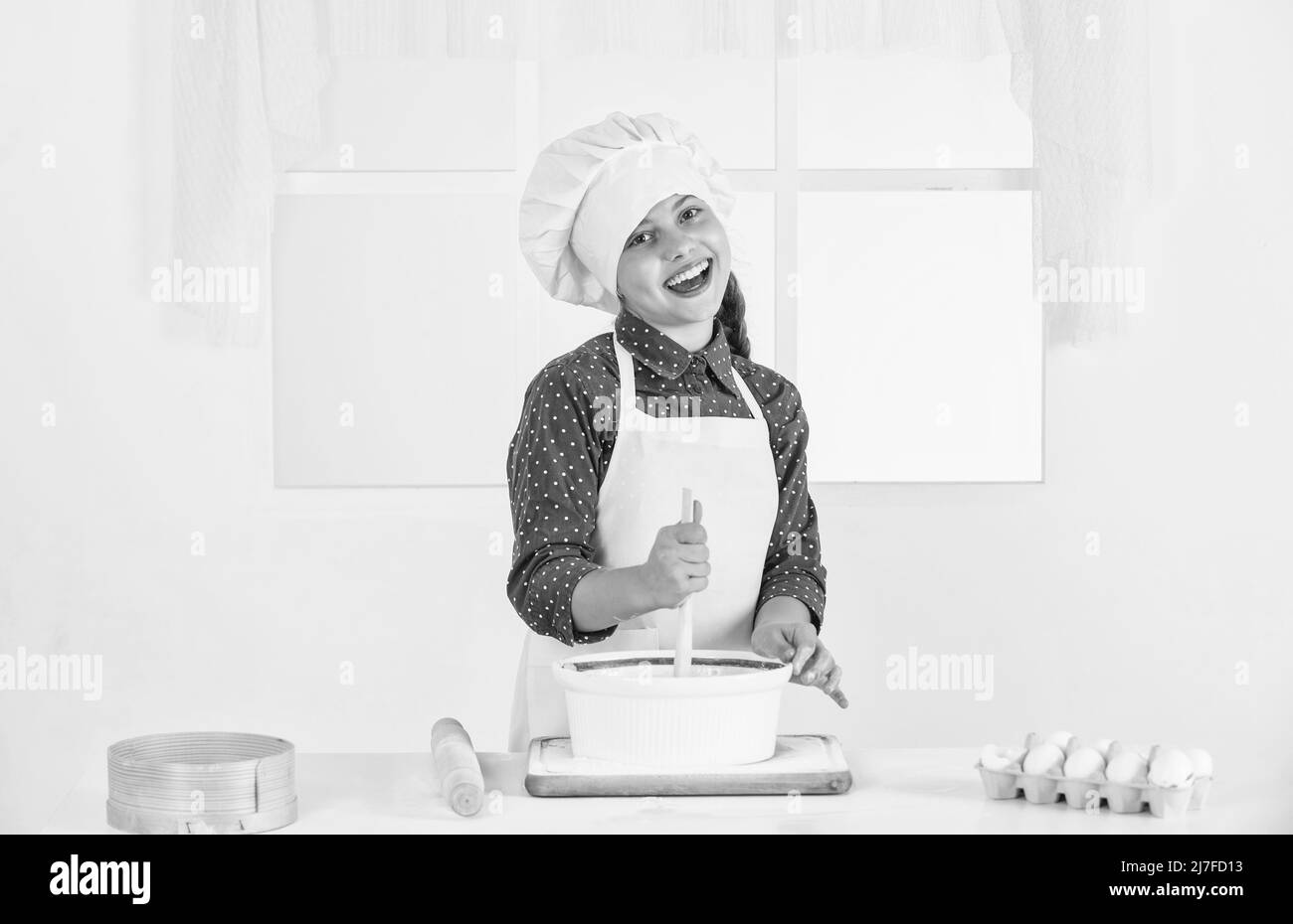 smiling teen girl in chef uniform cooking and baking, bakery Stock