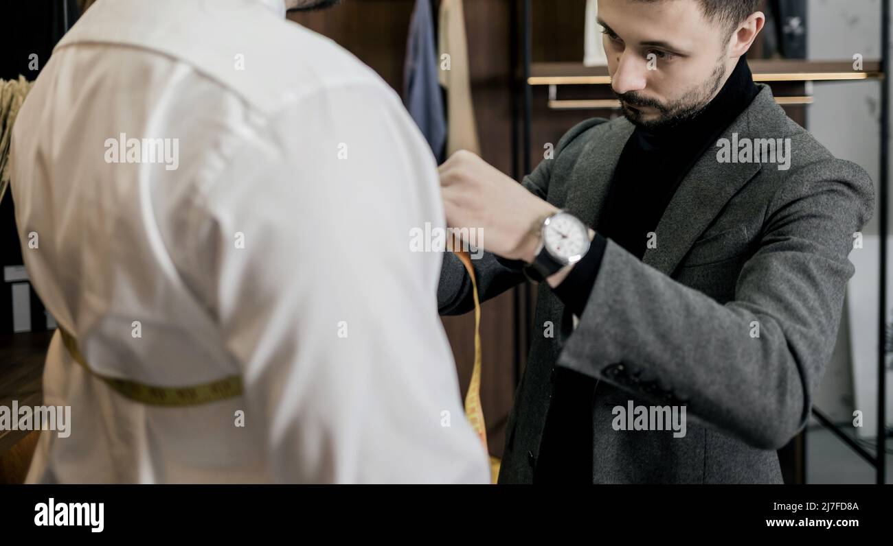tailor taking measurements for a man suit. bearded fashion designer in ...