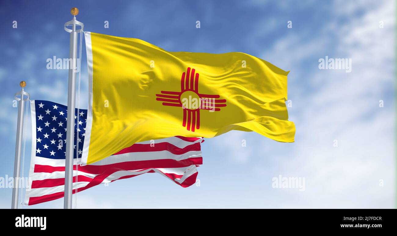 The New Mexico state flag waving along with the national flag of the United States of America. In the background there is a clear sky. New Mexico is a Stock Photo