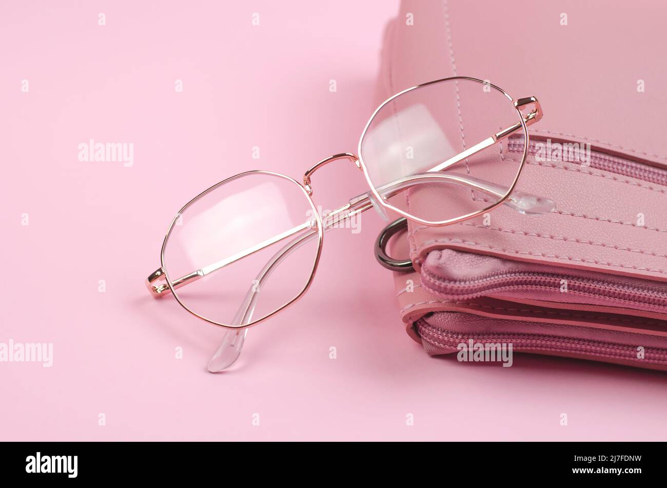 Stylish eyeglasses on a pink women's handbag, close-up Stock Photo