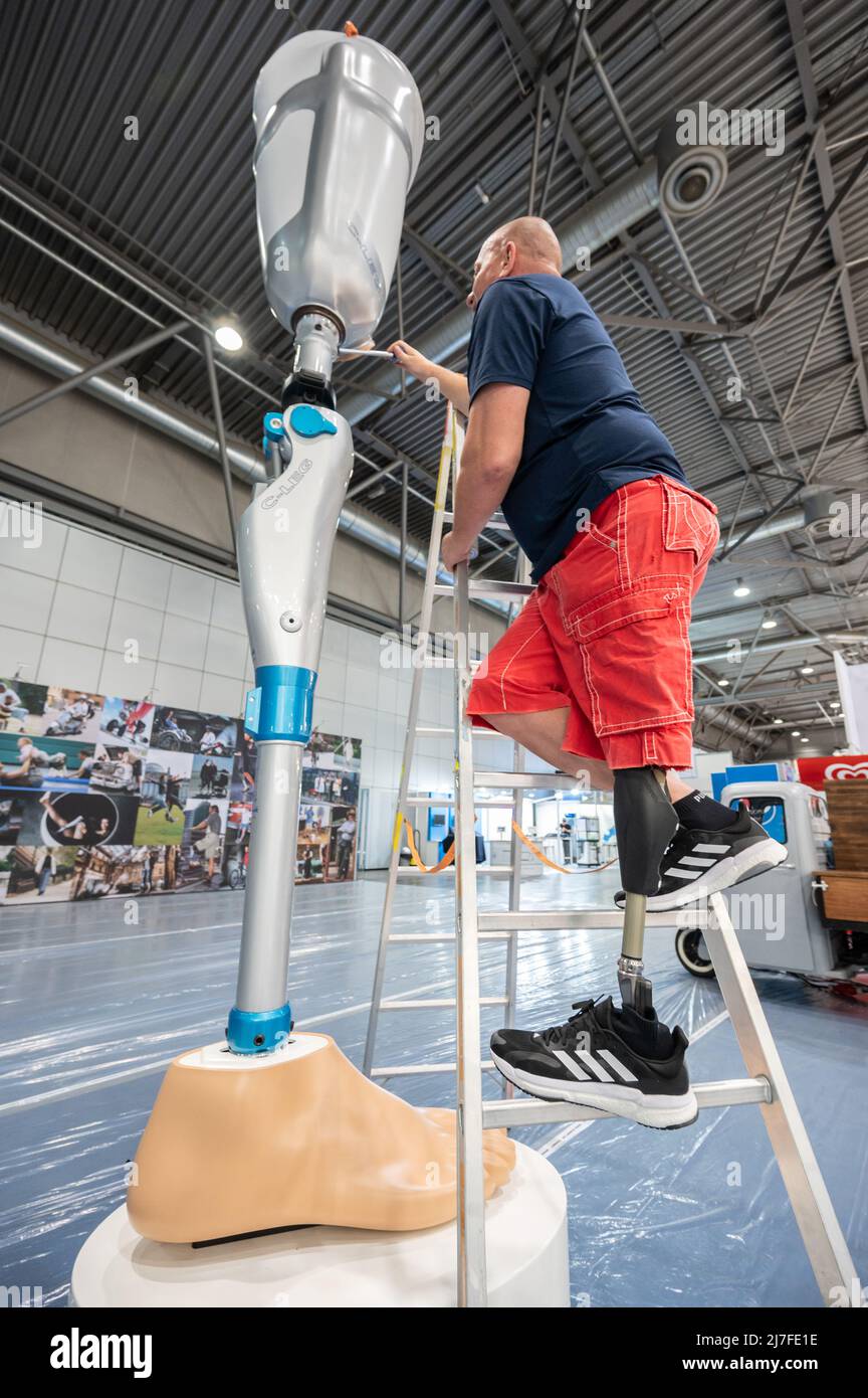 Leipzig, Germany. 09th May, 2022. Mathias Börner, Ottobock sales representative for Saxony and Thuringia, screws on an oversized model of a leg prosthesis. The Duderstadt-based company Ottobock is displaying a four-meter-high model of the C-Leg leg prosthesis to mark its 25th anniversary at OTWorld 2022, the world's leading trade fair for orthopaedic and rehabilitation technology. It was the world's first mechatronic knee joint. The C-Leg technology has now been used in more than 100,000 fittings worldwide. Credit: Christian Modla/dpa/Alamy Live News Stock Photo